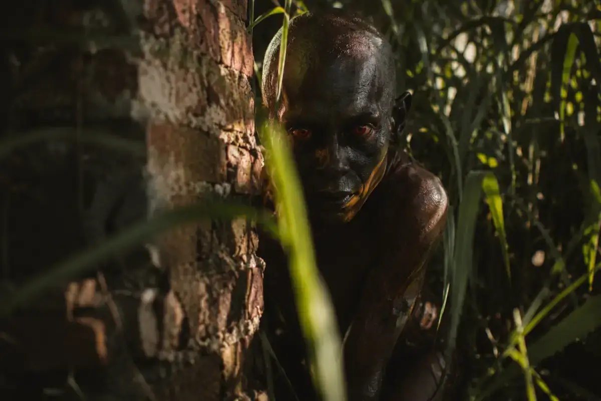 Ilustracija vanzemaljskog bića iz incidenta u Varginhi — humanoid tamne kože i velikih crvenih očiju, kako se krije u sjenci zapuštenog dvorišta u brazilskom gradu.